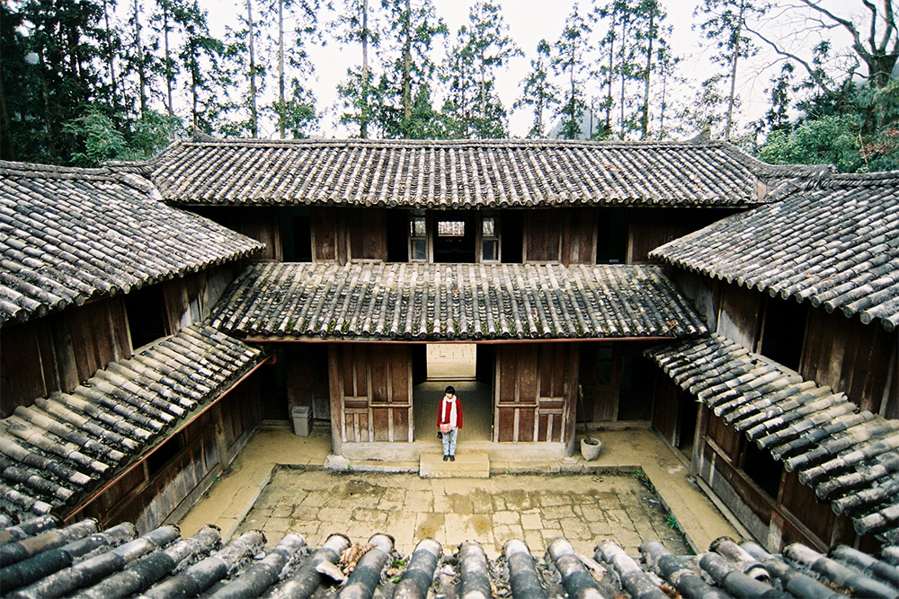 High-angle view of the central courtyard inside the Vuong Family Mansion, showcasing the traditional yin-yang tiled roofs and symmetrical wooden architecture in Ha Giang