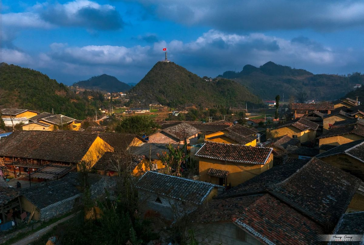 Overview of Lo Lo Chai Village with traditional earthen houses and Lung Cu Flag Tower on the mountain top, Ha Giang
