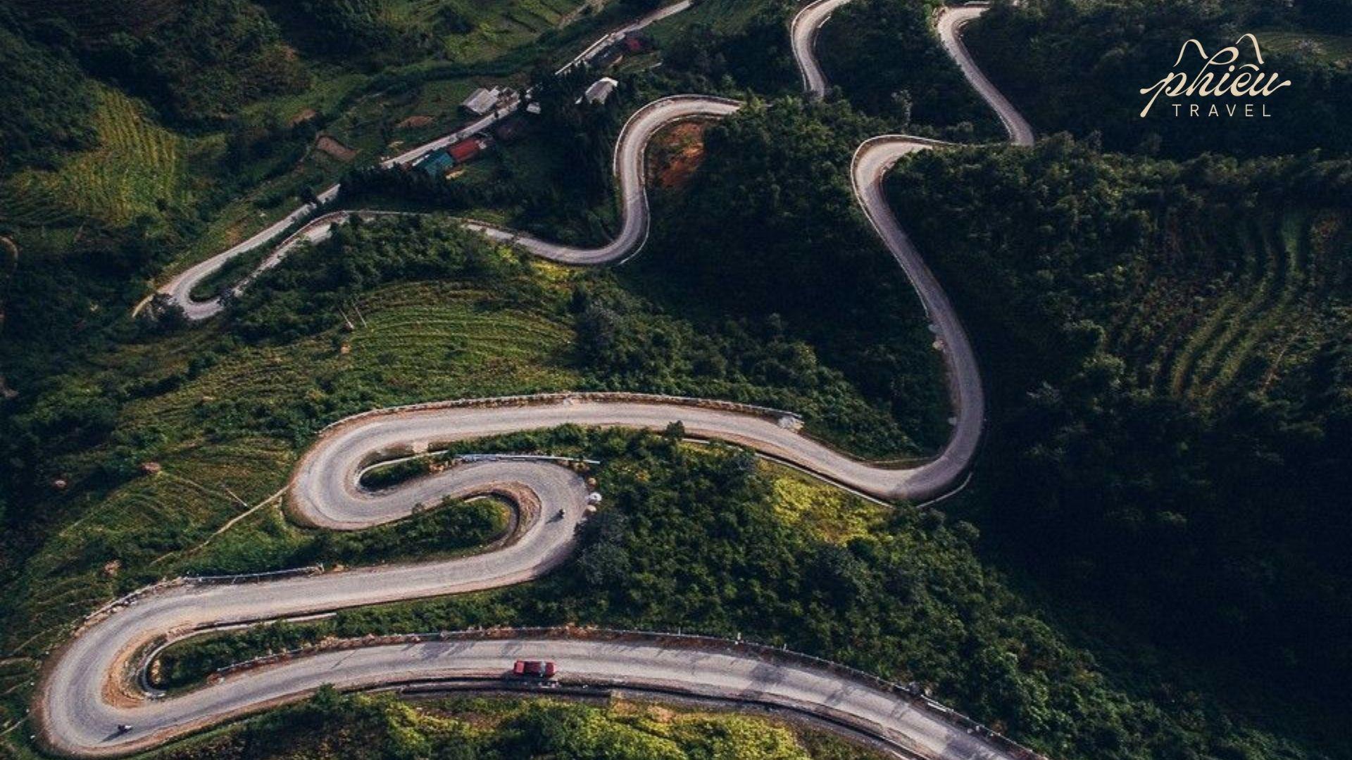 Aerial view of the Chín Khoanh Ramp, a dramatic winding mountain road with tight curves cutting through lush green hills in Ha Giang.