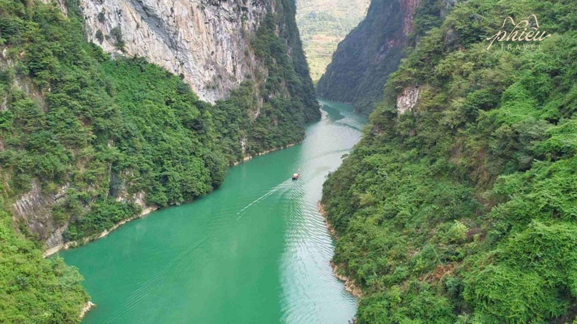 The emerald-green Nho Que River winds through Tu San Gorge, Southeast Asia’s deepest canyon, with mountains stretching into the distance.